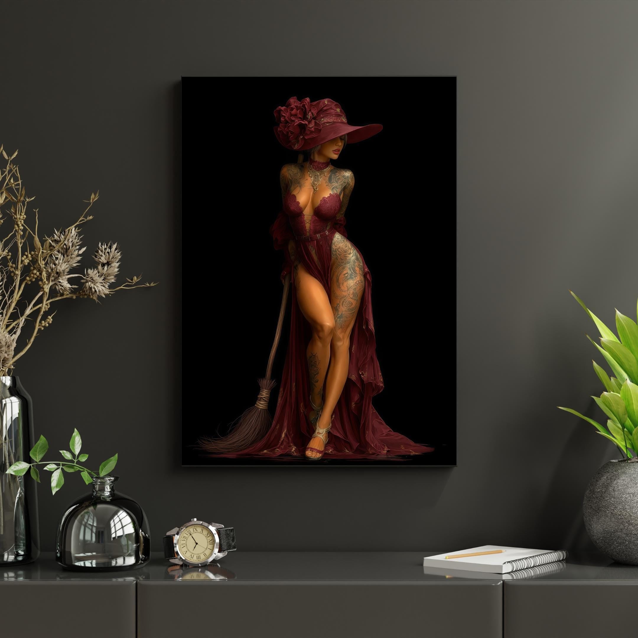 Sultry inked model as Halloween witch—burgundy velvet dress, massive flower hat, tattoos visible on skin, leaning on wooden broom against void.